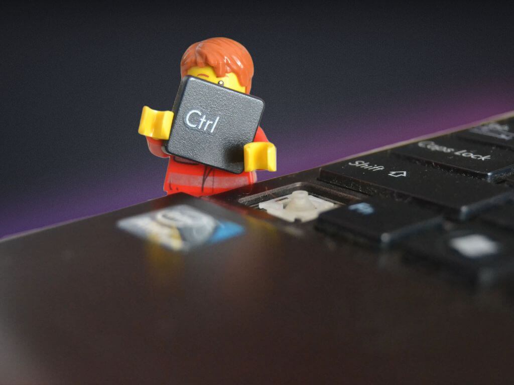 Um boneco lego segurando a tecla control de um teclado de notebook